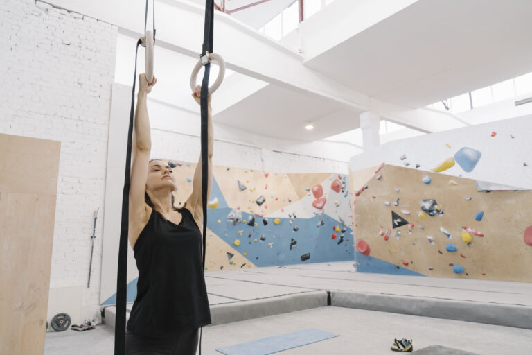 Lithuania, Vilnius, Woman doing stretching exercises before climbing on the rock wall
